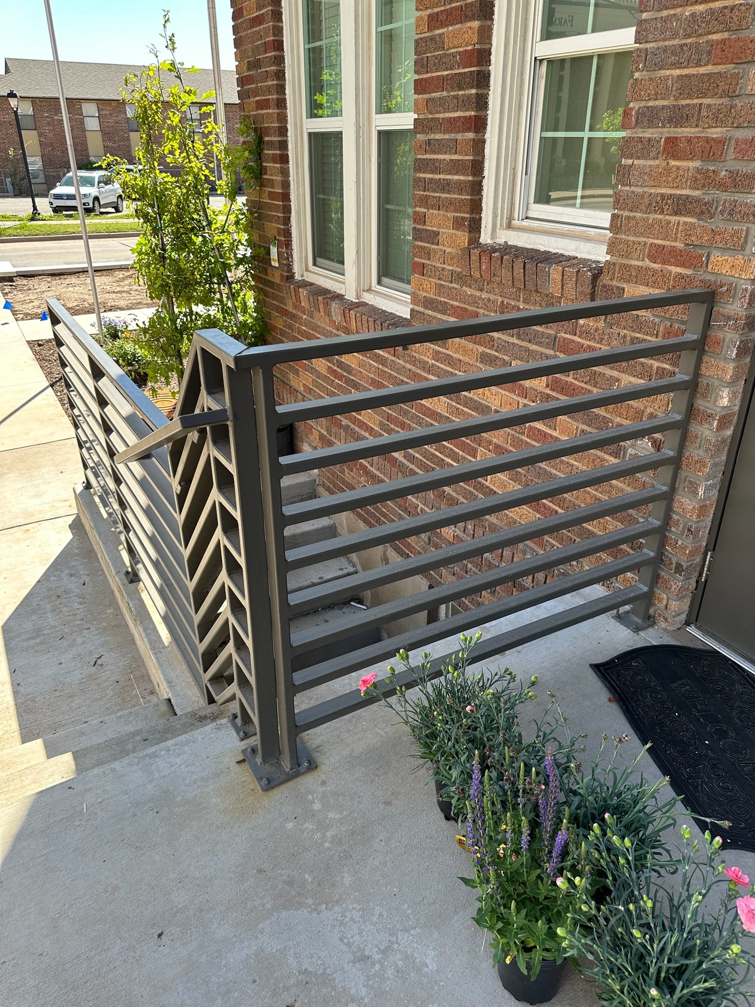 Custom black handrail installed at a brick building entrance