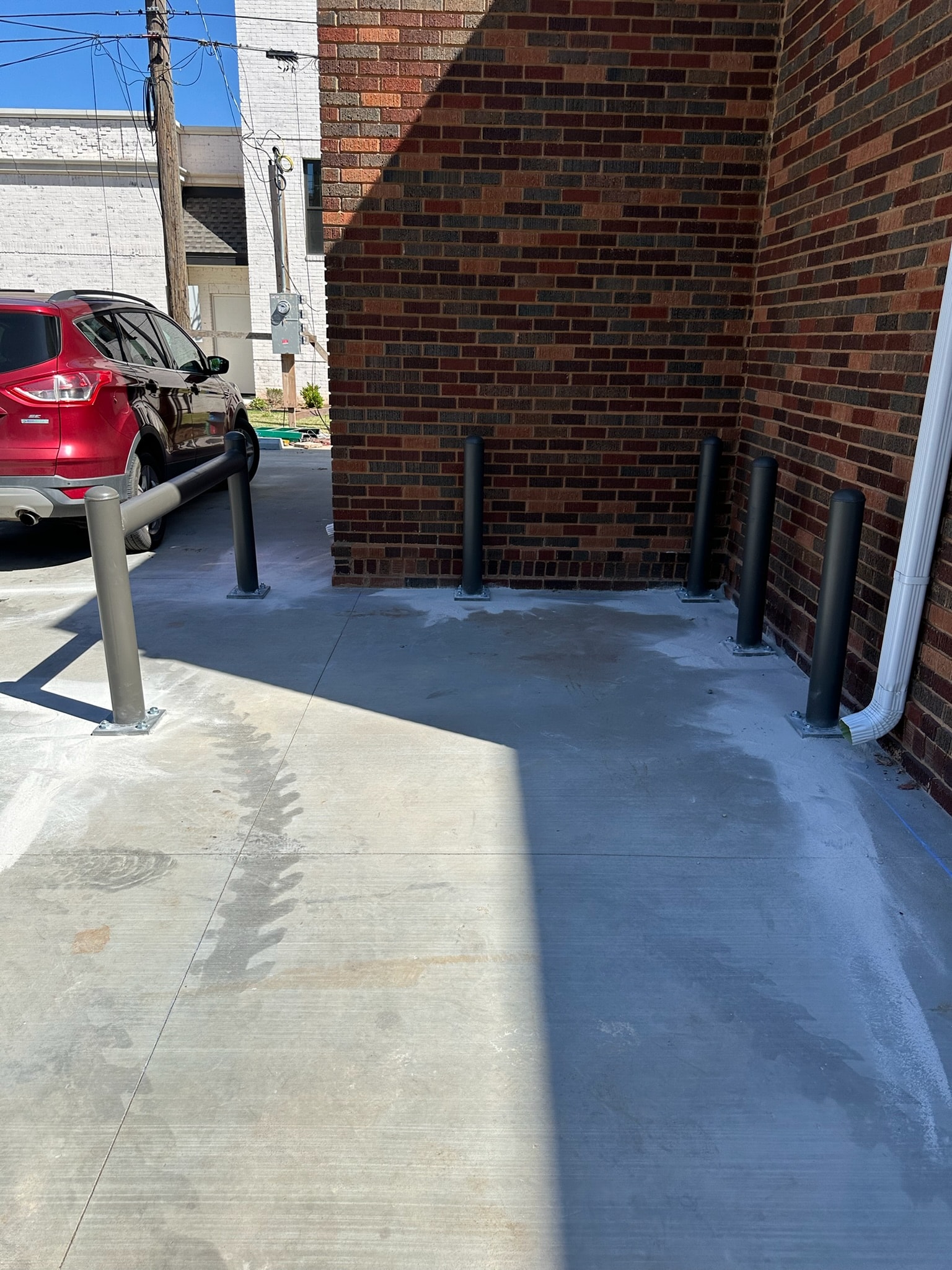 Commercial safety bollards installed beside a brick building service area