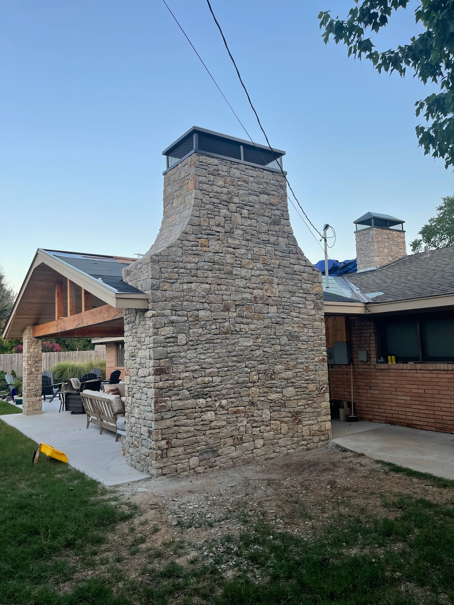Custom black steel chimney caps installed on a residential outdoor fireplace