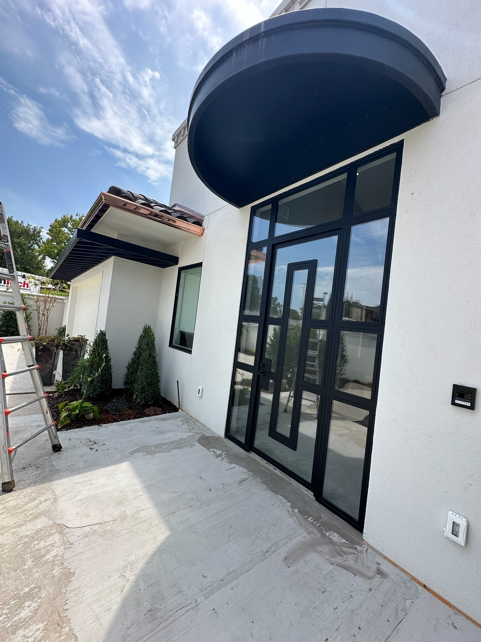 Custom curved black steel awning installed above a modern building entrance