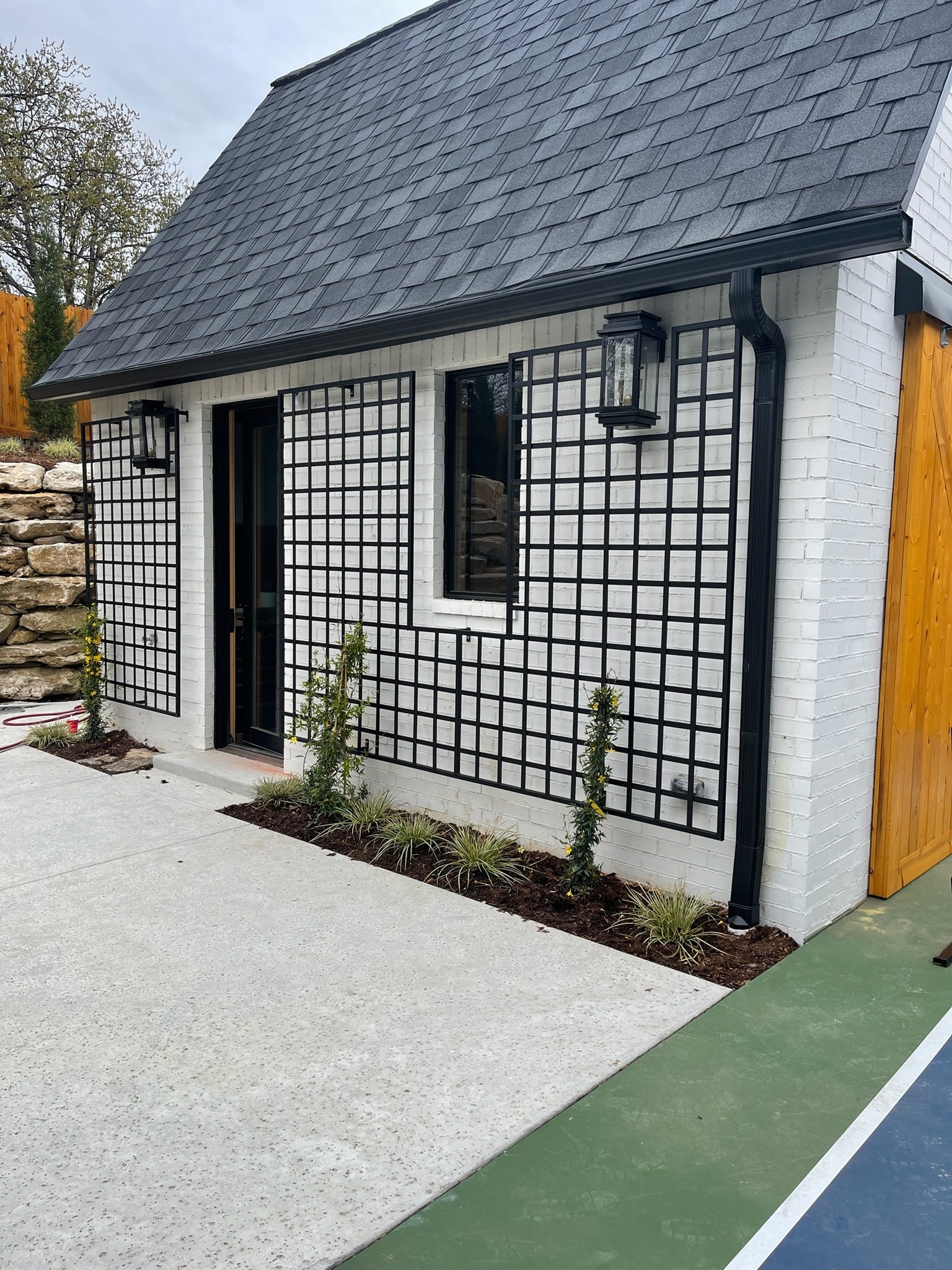 Custom black steel exterior trellis panels installed on a white brick building