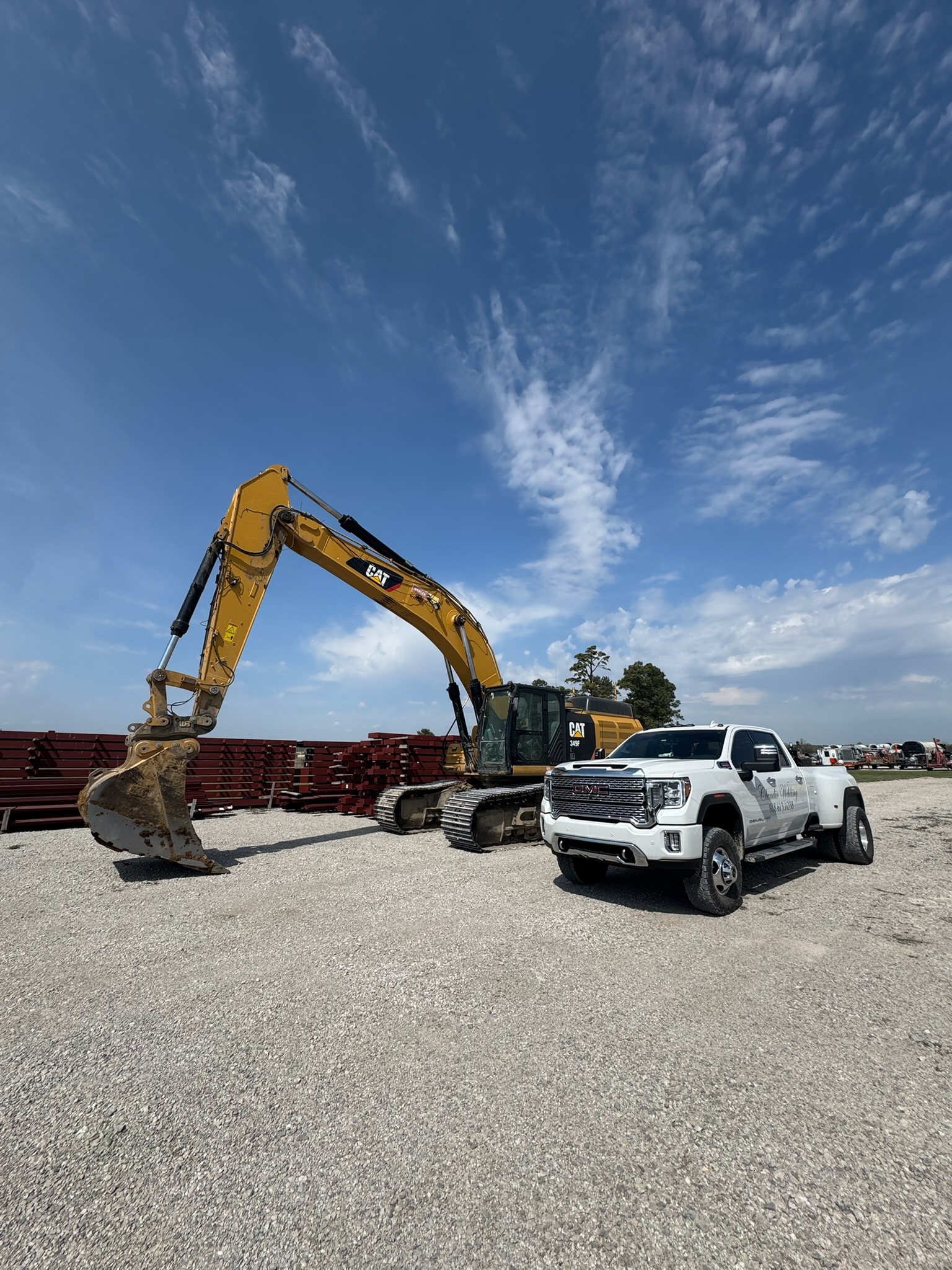 Claudio Welding work truck and CAT excavator at an equipment yard