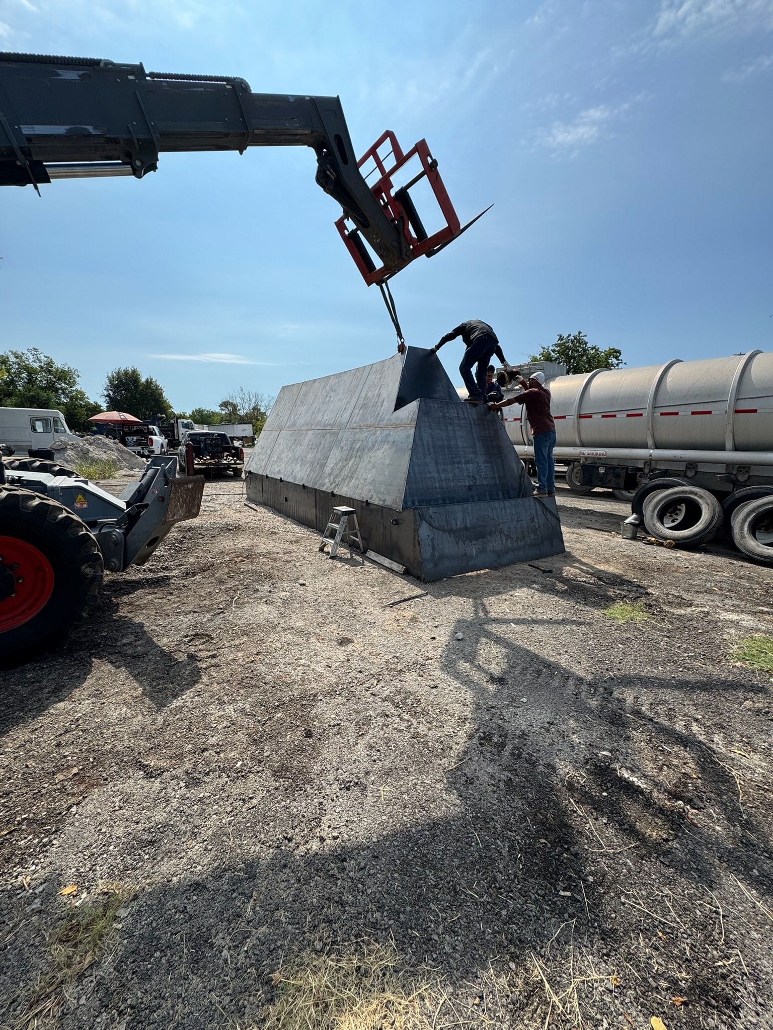 Crew assembling a large custom steel structure with heavy equipment