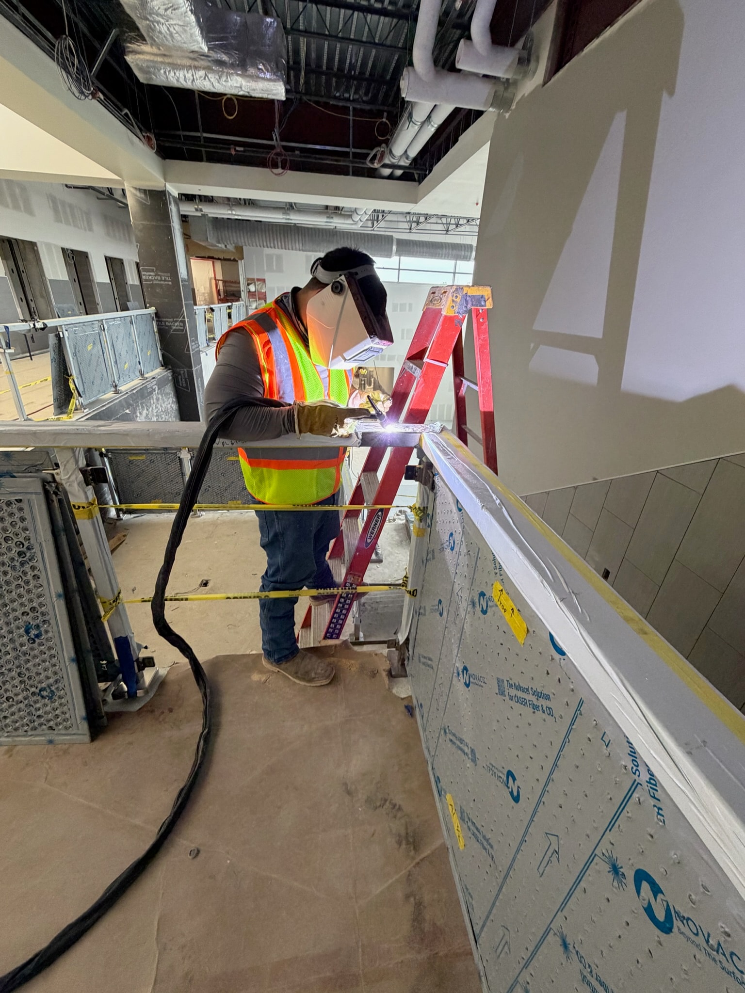 Welder fabricating a stair rail inside a commercial building