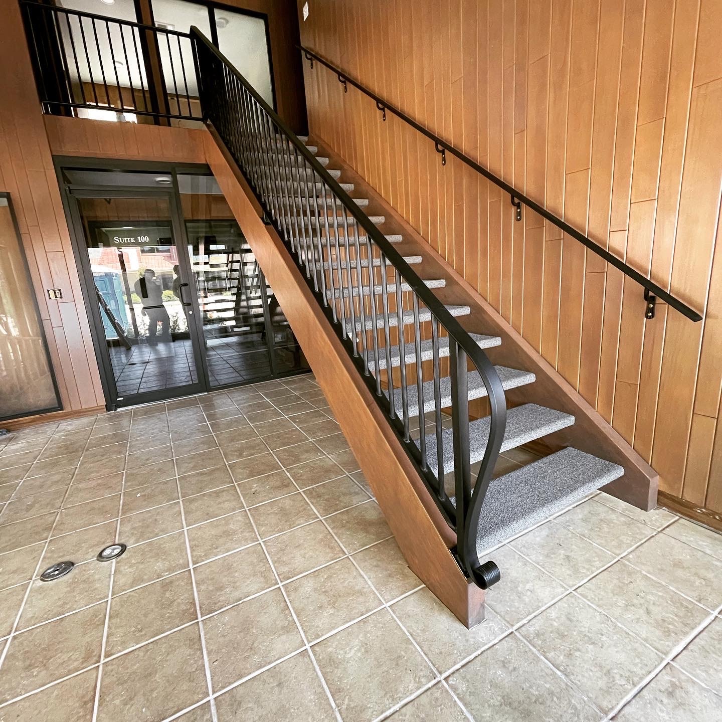 Interior staircase with black steel guardrail and wall-mounted handrail