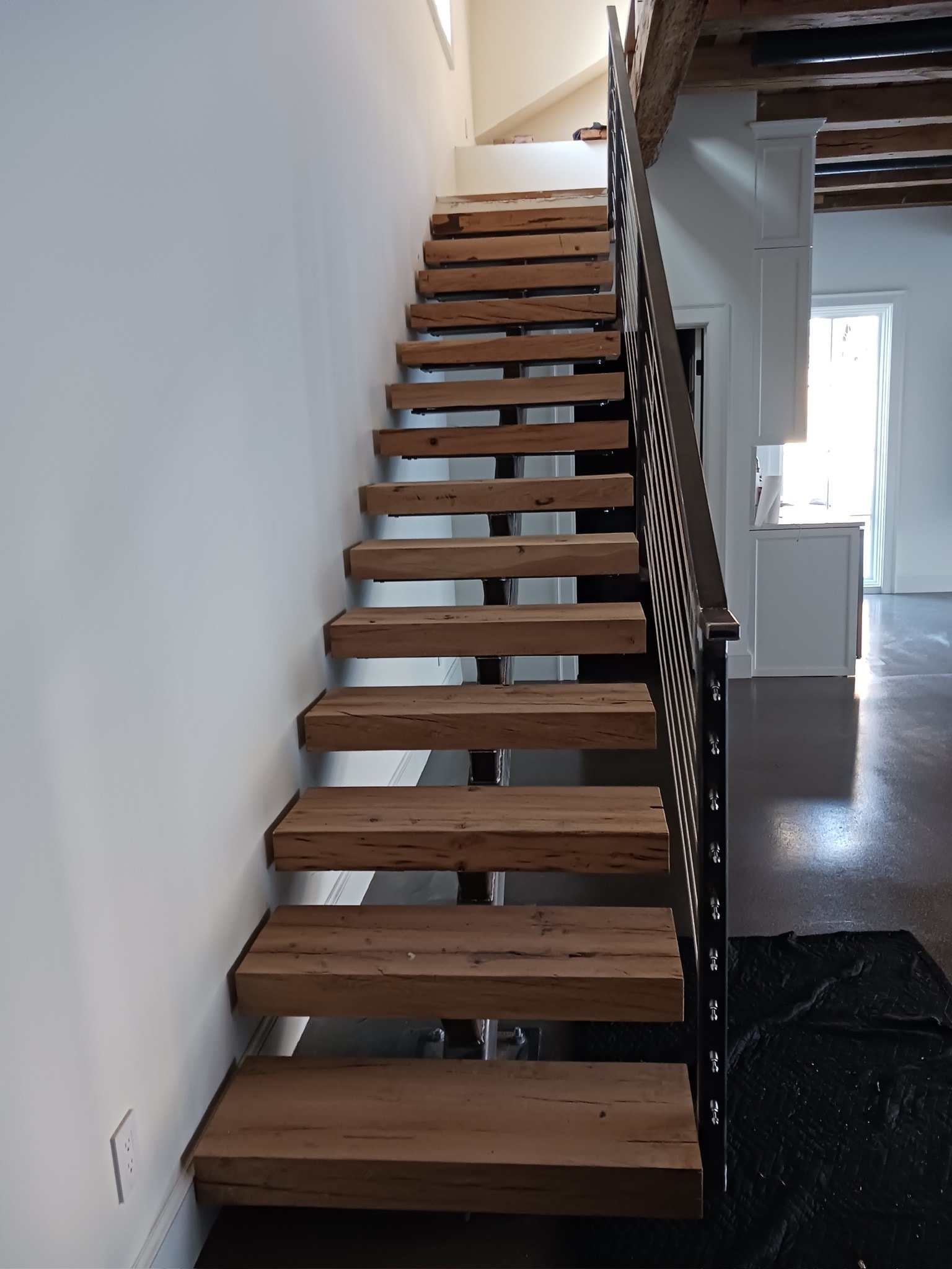 Open-riser wood staircase with custom black steel railing