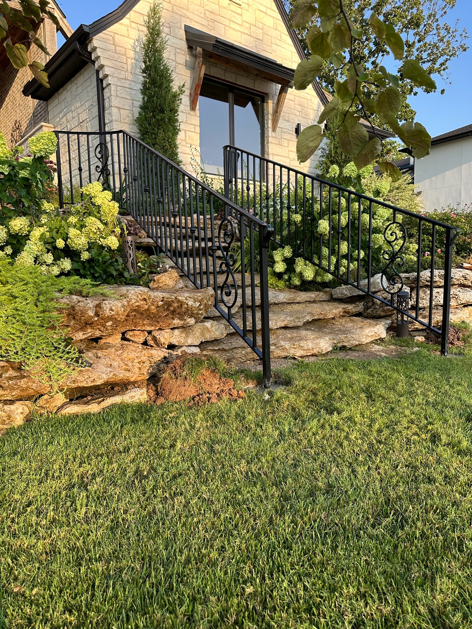 Custom black ornamental railings and guards installed along landscaped residential stone steps