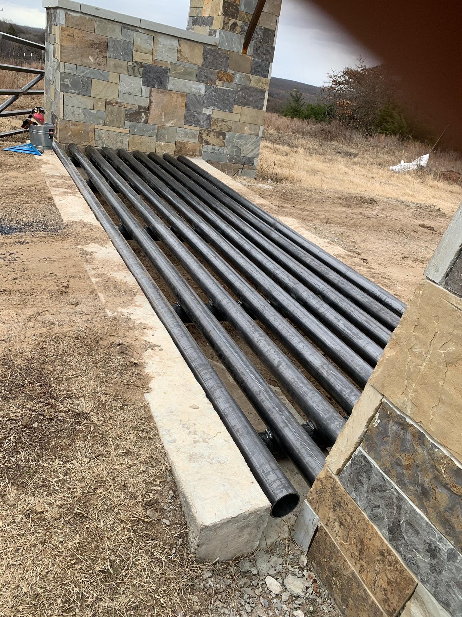 Steel pipe installation prepared at a rural stone entrance project