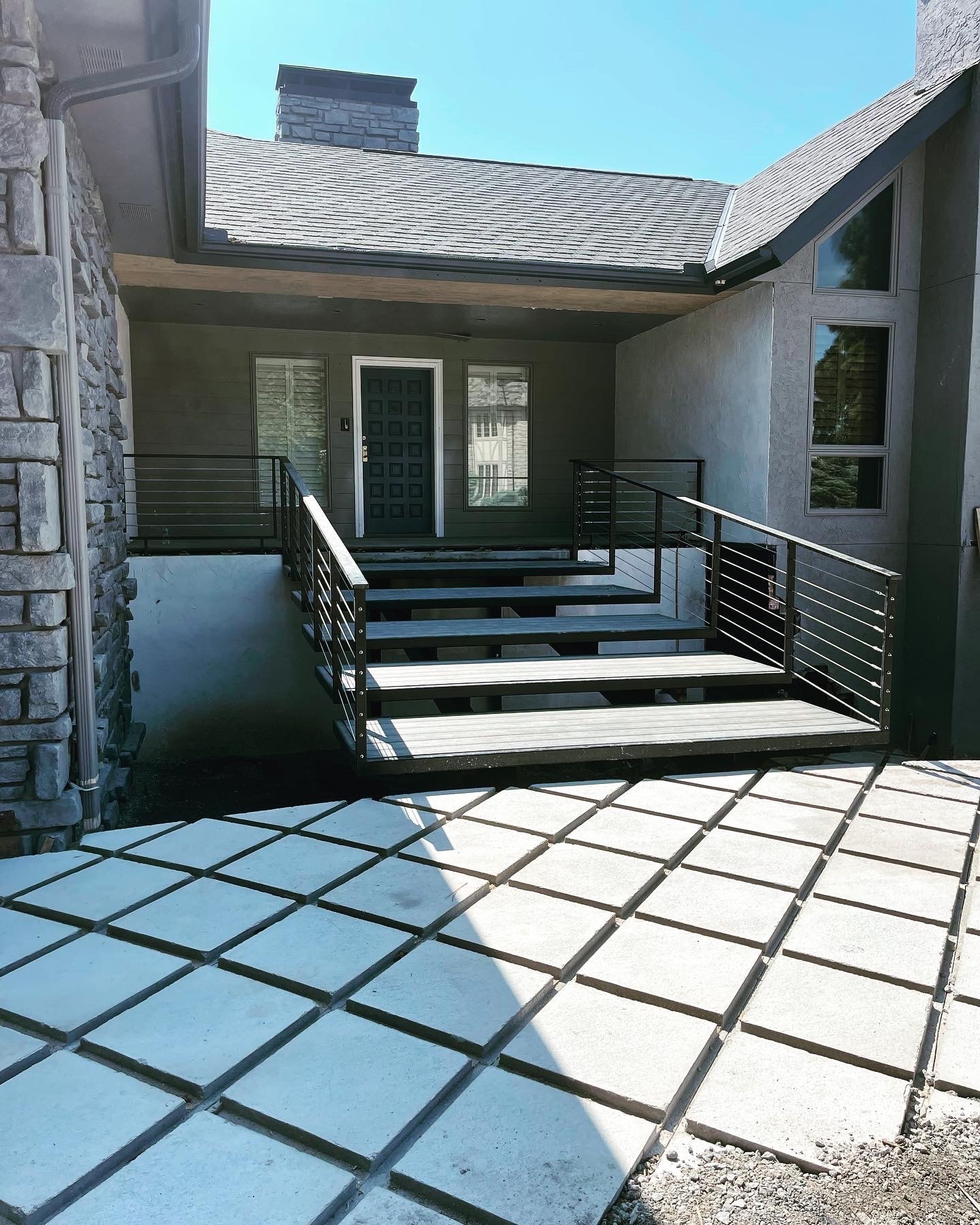 Custom black steel railing installed at a residential stone entry