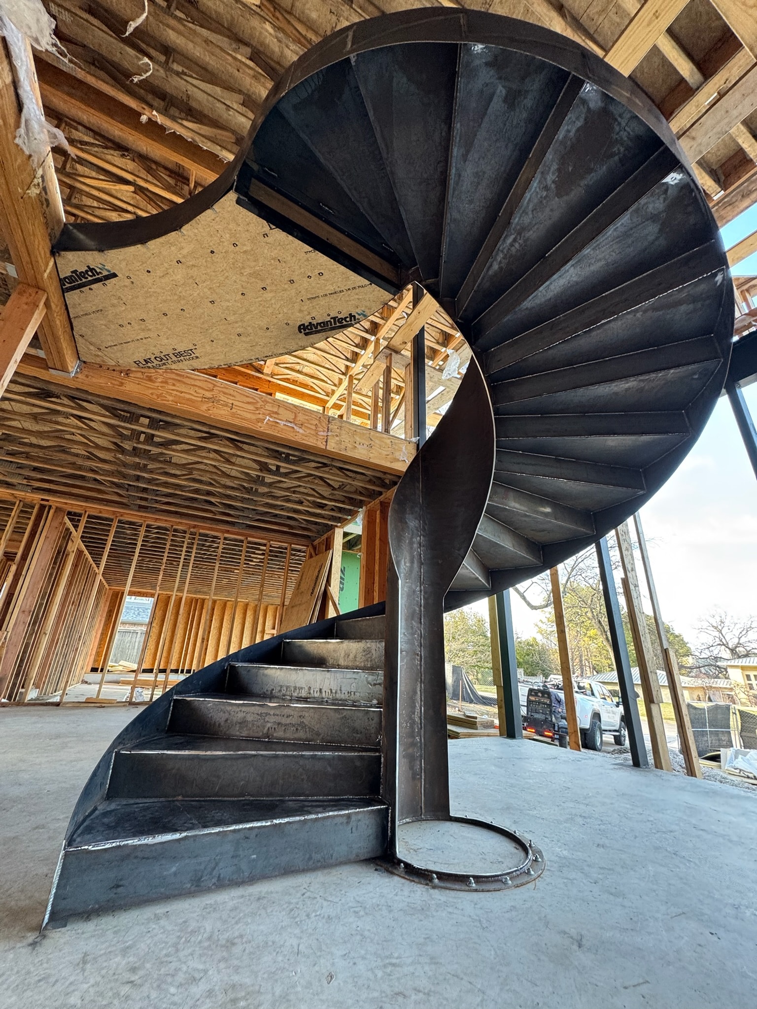 Custom black steel spiral staircase installed in a timber-framed construction space